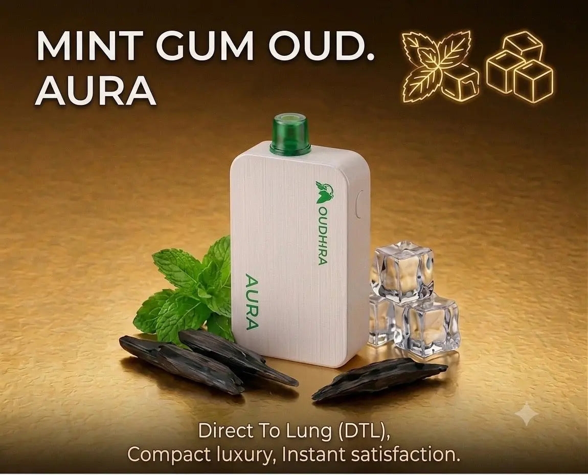 A white Udhira Aura direct to lung vape device with a green cap, displayed on a golden background with mint leaves, ice cubes, and dark pods. Text overlays read 'MINT GUM OUD.