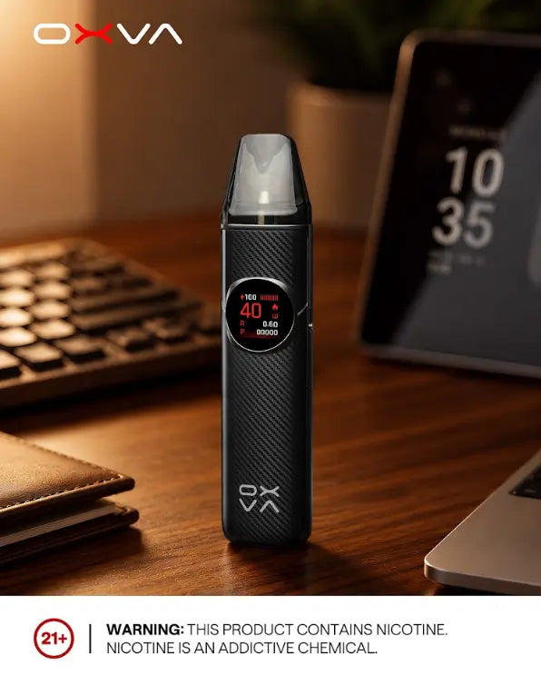 A black OXVA electronic vape device with a carbon-fiber textured grip and a digital display, standing on a wooden desk with a keyboard, wallet, and tablet in the background. ORDER NOW AND GET 20% OFF